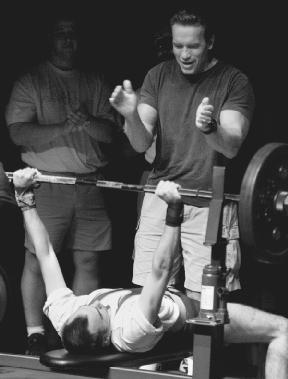 Arnold Schwarzenegger supports Willie McKinney during the bench press competition of the 1999 Special Olympics World Games. AP/Wide World Photos. Reproduced by permission.
