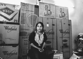 Nisha Sharma, at her home in India, sits in front of boxes of goods bought as her wedding gift. AP/Wide World Photos. Reproduced by permission.